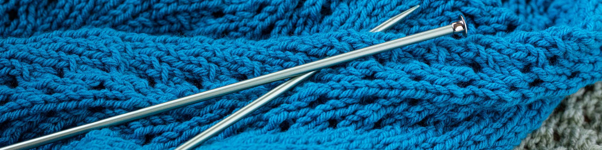 detail of knitting needles and two knit prayer shawls